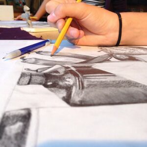 A closeup of someone's hand holding a pencil and sketching