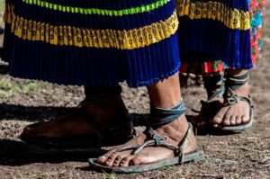 A closeup of the feet of people wearing colorful dresses and leather thong sandals