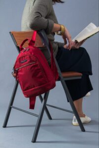 Photo of someone sitting down with a backpack and reading a book
