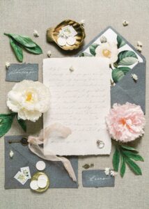 White letter surrounded by flowers with a silver ring sitting on top