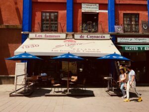 A photo of an cafe awning on a street, labeled "Los famosos de Coyoacán" 
