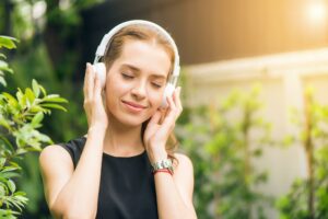 White woman with white headphones listening to music
