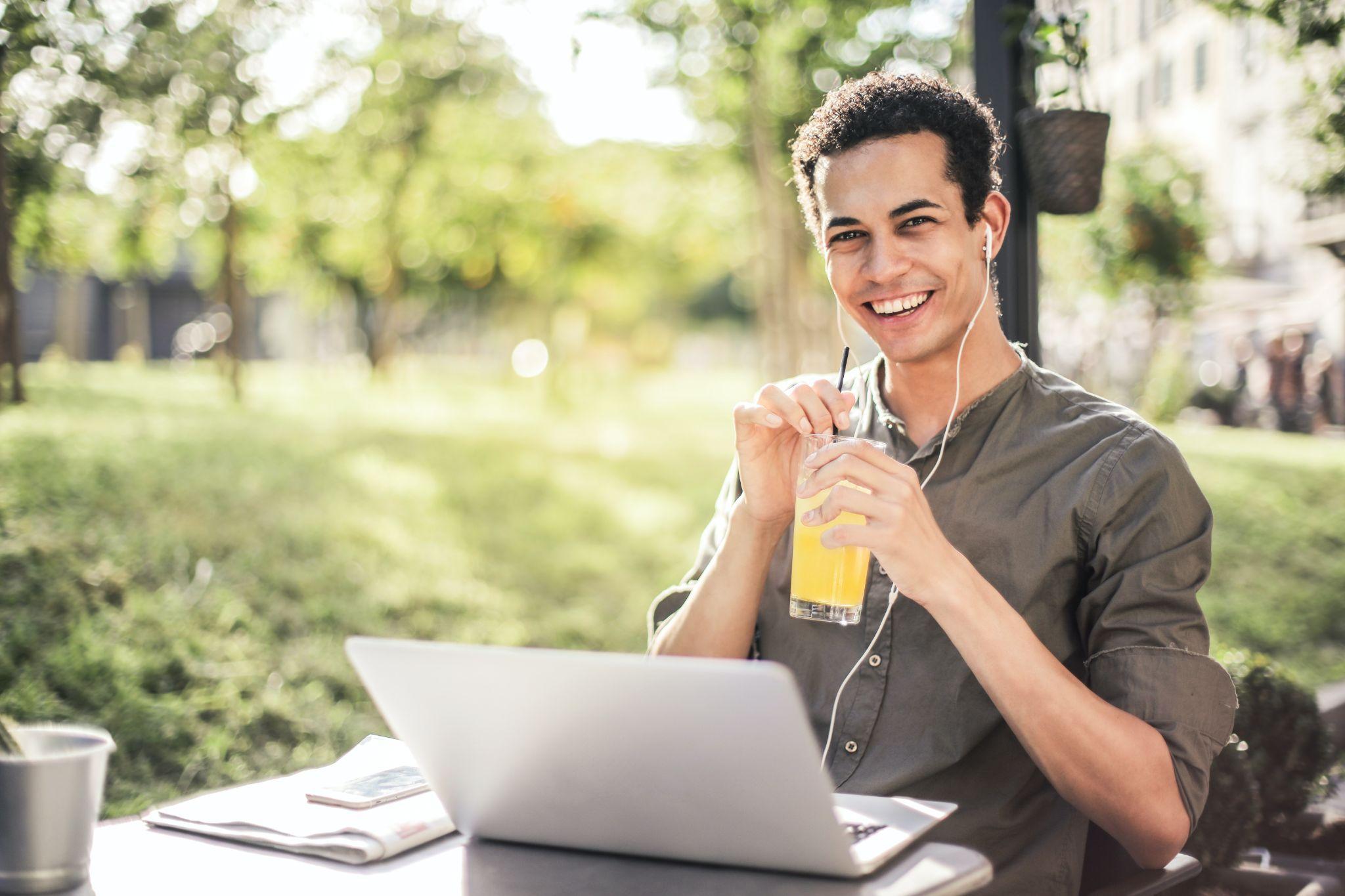 Photo of men drinking juice and using his laptop
