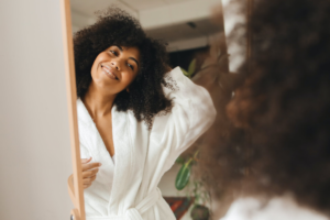 Photo of black woman in a white robe smiling in the mirror