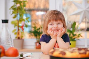Photo of a toddler girl smiling and sitting at a table