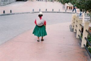 A woman walking down the street, carrying a bundle on her back