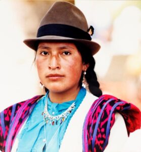 An indigenous woman wearing a hat and bright clothes
