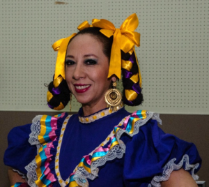 A dancer decked out in a blue dress and yellow ribbons in her hair