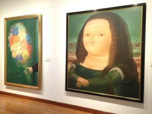 Large paintings on the wall of a museum by Frenando Botero