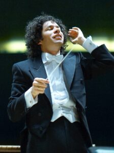 A photo of an orchestra conductor in a tuxedo conducting
