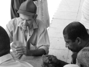 A black-and-white photo of two men sitting outside playing cards