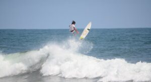 A man doing a jump over an ocean wave on a board