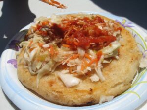 A pupusa on a plate with toppings