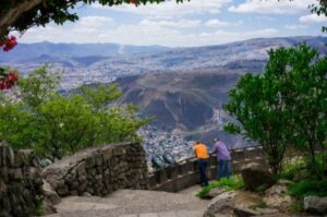 Two people leaning on a railing overlooking a mountainous city