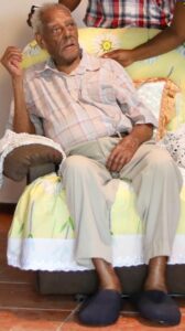 A photo of Water Ferguson, sitting in a recliner wearing slippers