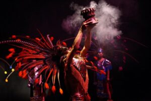 A woman in an Aztec headdress raises incense