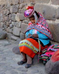 A Peruvian woman in colorful clothing sitting outside