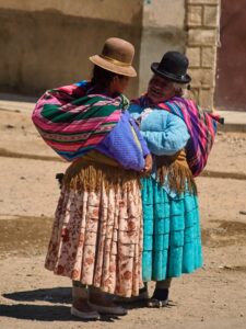 Two women with colorful bundles on their back meet in the street