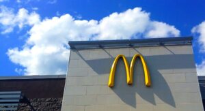 McDonald's logo on a building with a blue sky and white clouds in the background.