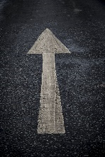 White painted arrow on black pavement