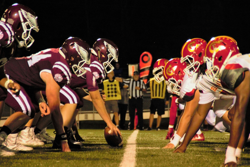 Football players on opposing teams line up against each other on the field