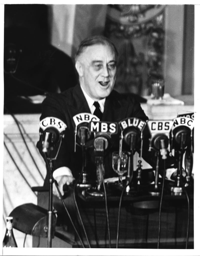 Black and white picture of FDR speaking into many microphones