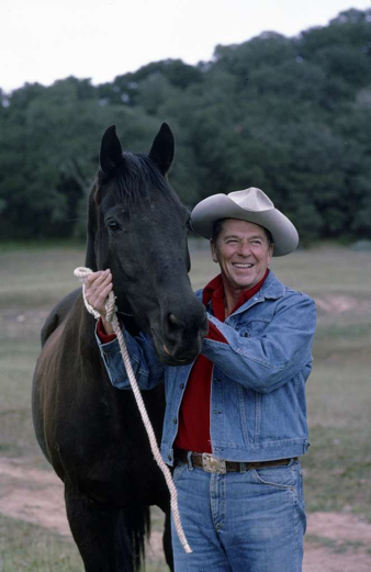 President Reagan in a jeans, a jean jacket, and cowboy hat with his horse