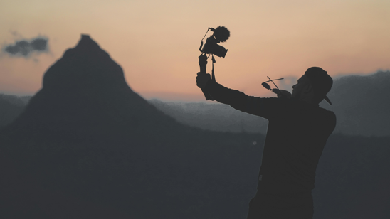 Silhouette photo of a man taking a picture of himself while holding the camera up high
