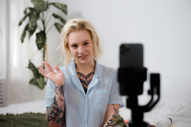 A woman waves at a phone on a stand