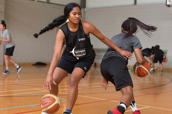 Two women play basketball