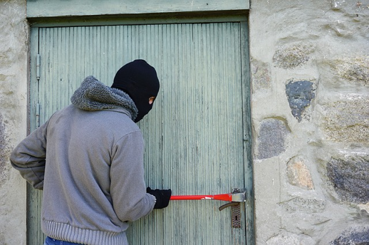 A burglar uses a crowbar to get into a door