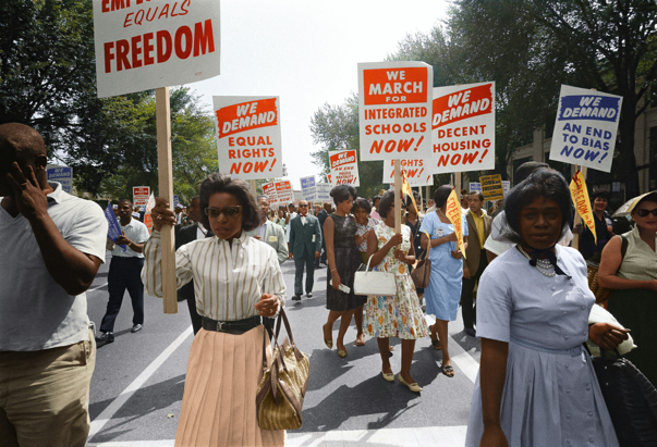 Black protesters march while holding signs