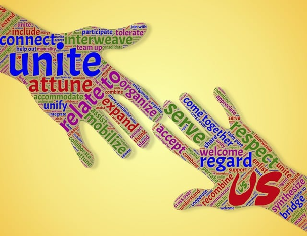 Two hands reach toward each other. One has words on it like "unite" and "relate to" while the other has words like "welcome," "regard," and "us."