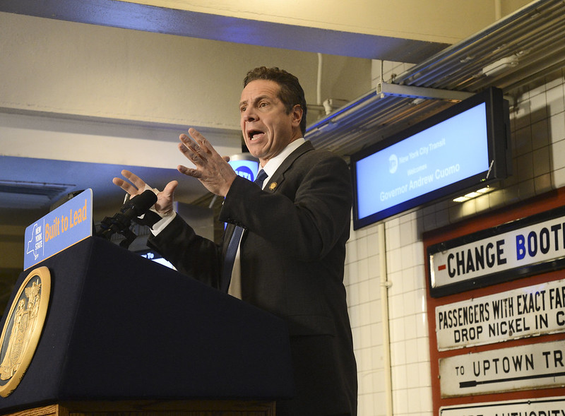 Governor Andrew Cuomo speaks at a podium in a New York City subway.